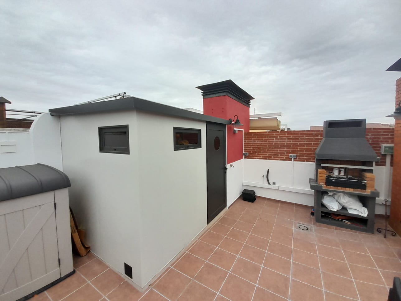 Caseta de terraza con baño, base de hormigón, baldosas porcelánicas y cerramiento con panel sándwich aislante de 5 cm, vidrios bronce